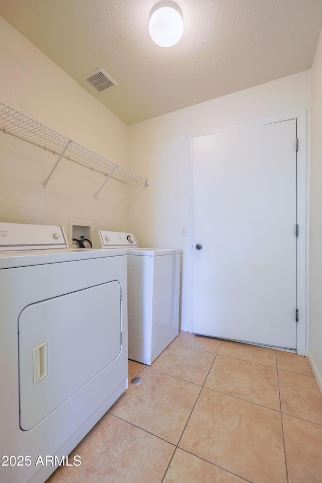 washroom featuring light tile patterned floors, washing machine and dryer, and a textured ceiling