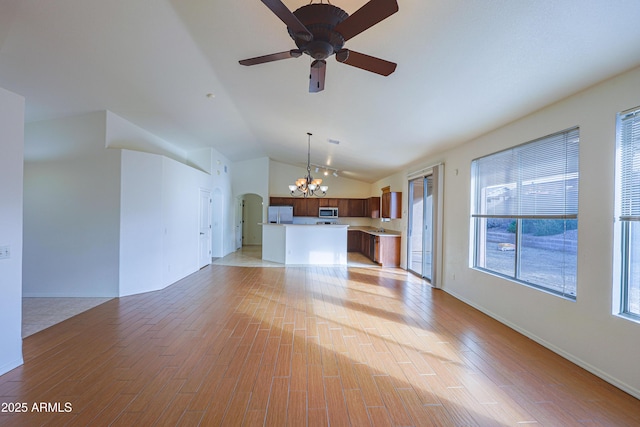 unfurnished living room with lofted ceiling, light hardwood / wood-style flooring, and ceiling fan with notable chandelier