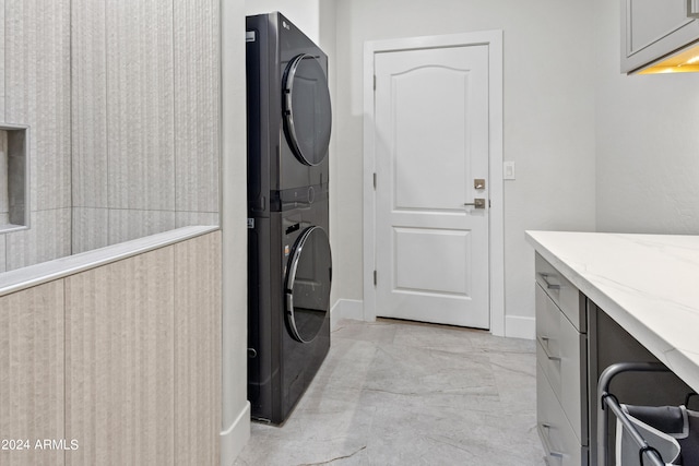 washroom featuring cabinets and stacked washer / dryer