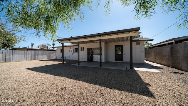 back of house with strapped water heater and a patio area