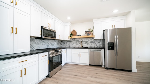 kitchen featuring light hardwood / wood-style flooring, white cabinets, stainless steel appliances, and backsplash