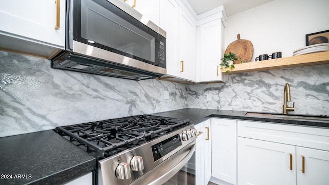 kitchen featuring decorative backsplash, white cabinetry, stainless steel appliances, and sink