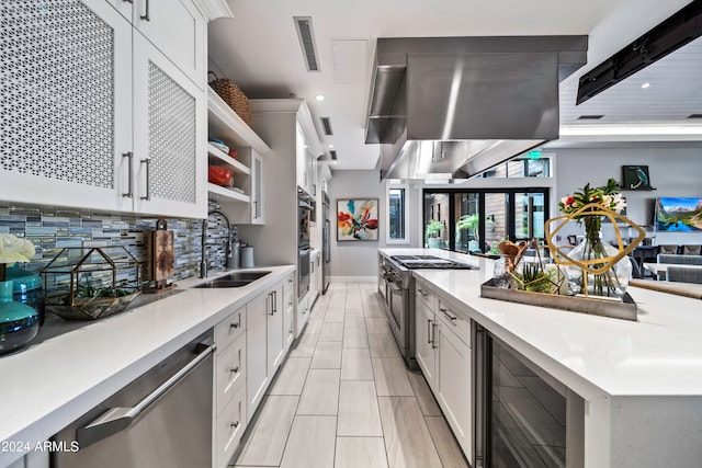 kitchen with wall chimney exhaust hood, white cabinets, wine cooler, and appliances with stainless steel finishes