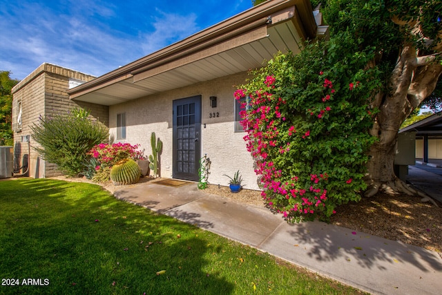 view of exterior entry with central AC and a yard