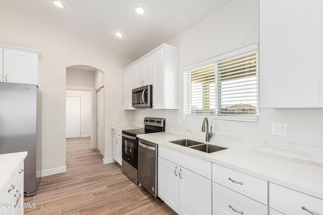 kitchen featuring light hardwood / wood-style floors, sink, light stone countertops, appliances with stainless steel finishes, and white cabinets