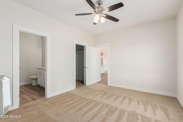 unfurnished bedroom with ceiling fan, carpet floors, ensuite bath, a spacious closet, and a closet