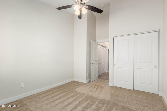 unfurnished bedroom with ceiling fan, a closet, and light carpet