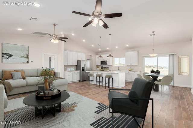 living room featuring ceiling fan, sink, light hardwood / wood-style floors, and high vaulted ceiling