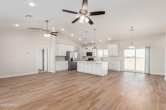 kitchen featuring white cabinets, appliances with stainless steel finishes, a kitchen island, hanging light fixtures, and light wood-type flooring