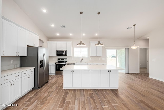 kitchen featuring white cabinetry, hanging light fixtures, stainless steel appliances, and a kitchen island