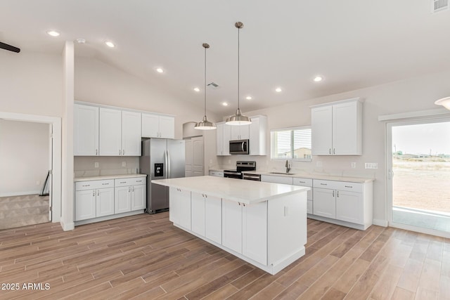 kitchen with pendant lighting, a kitchen island, sink, white cabinetry, and appliances with stainless steel finishes