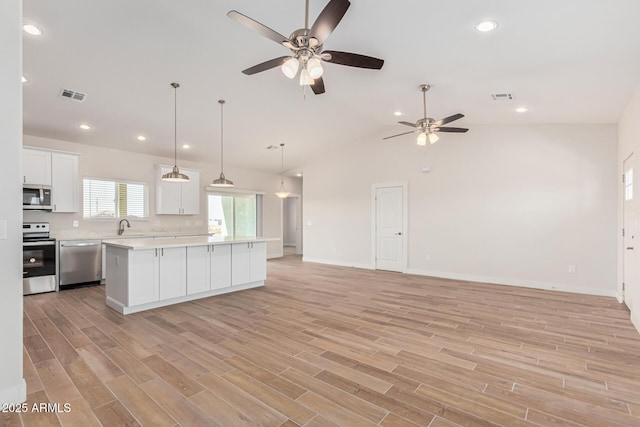 kitchen featuring white cabinets, light wood-type flooring, stainless steel appliances, and a center island