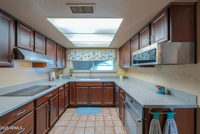 kitchen with appliances with stainless steel finishes, sink, a textured ceiling, and light tile patterned floors