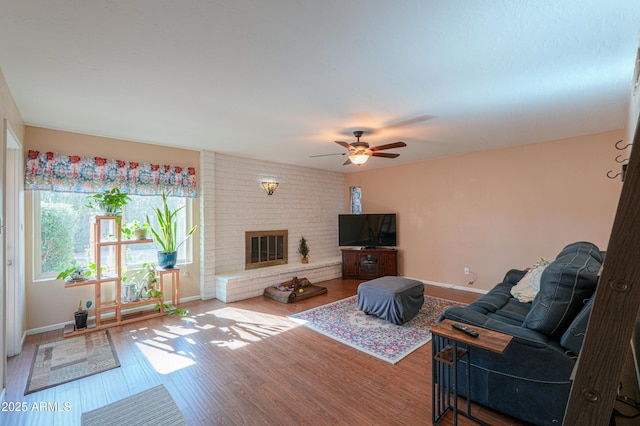 living room with hardwood / wood-style flooring, a brick fireplace, and ceiling fan