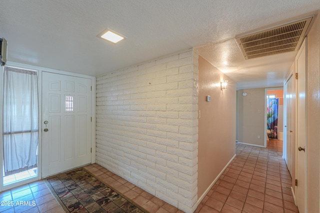 foyer featuring brick wall, a textured ceiling, and light tile patterned floors