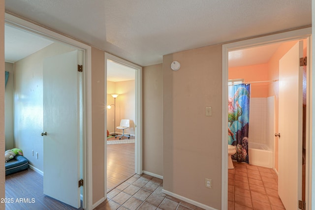 hallway featuring a textured ceiling and light tile patterned floors