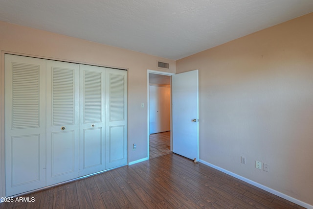 unfurnished bedroom featuring dark hardwood / wood-style floors, a closet, and a textured ceiling