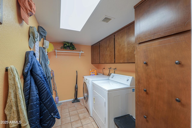 laundry area featuring a skylight, washer and clothes dryer, cabinets, and light tile patterned flooring