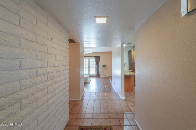 hallway featuring light tile patterned flooring, a textured ceiling, and french doors