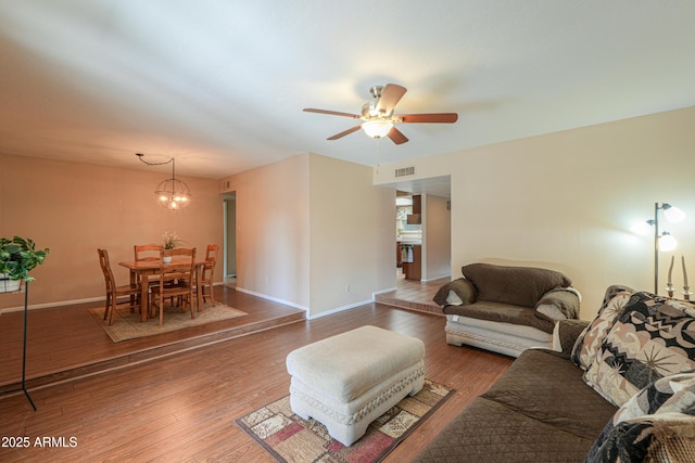 living room with hardwood / wood-style flooring and ceiling fan with notable chandelier