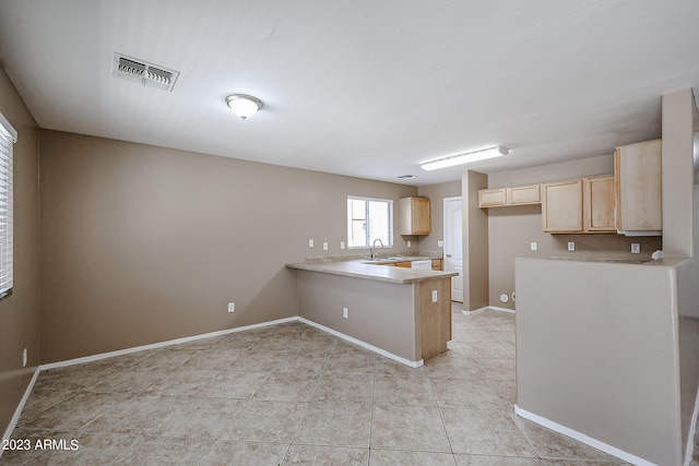 kitchen featuring light tile patterned floors, kitchen peninsula, sink, and light brown cabinetry