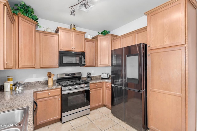 kitchen featuring light tile patterned flooring, visible vents, black appliances, and a sink