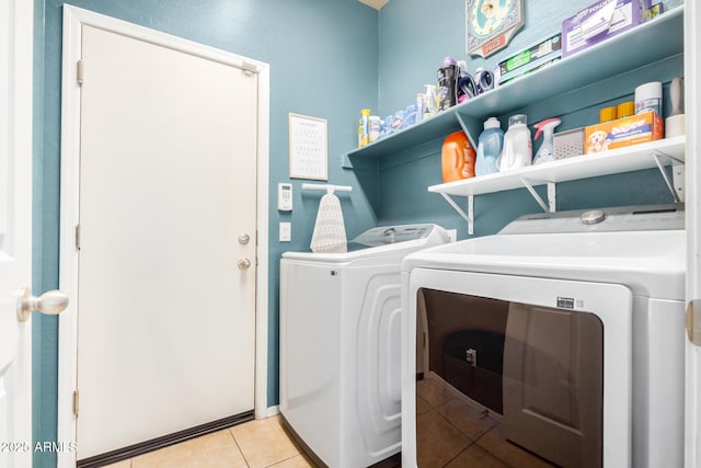 clothes washing area featuring laundry area, light tile patterned floors, and washer and clothes dryer