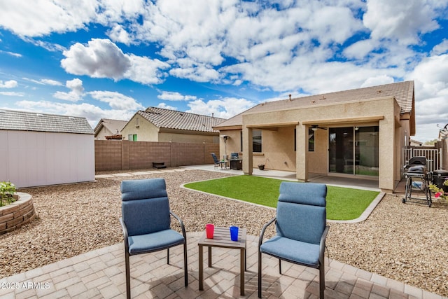 rear view of house with a shed, stucco siding, a fenced backyard, an outdoor structure, and a patio