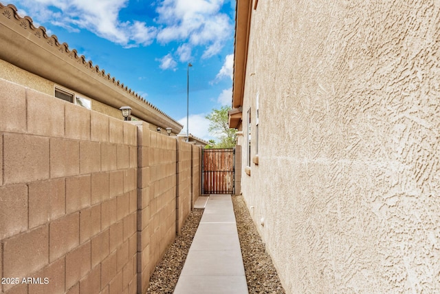 view of property exterior with a gate, stucco siding, and fence