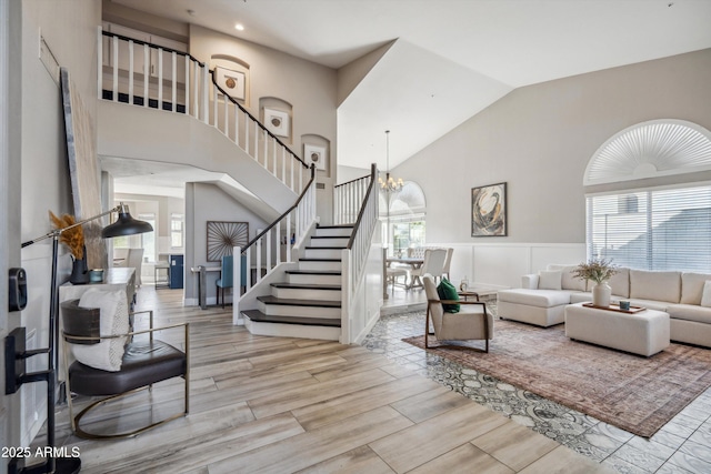 living area featuring a chandelier, stairway, light wood-type flooring, and a healthy amount of sunlight