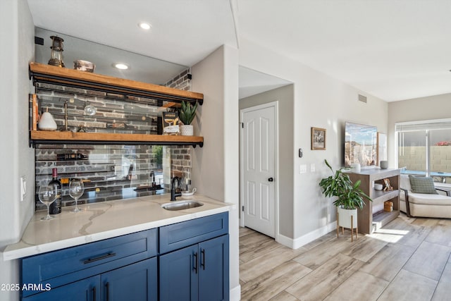 bar with a sink, visible vents, baseboards, wood tiled floor, and wet bar