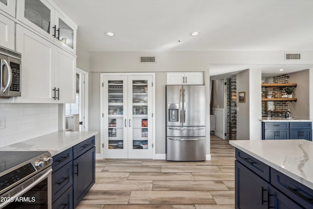 kitchen featuring glass insert cabinets, white cabinetry, appliances with stainless steel finishes, and blue cabinets