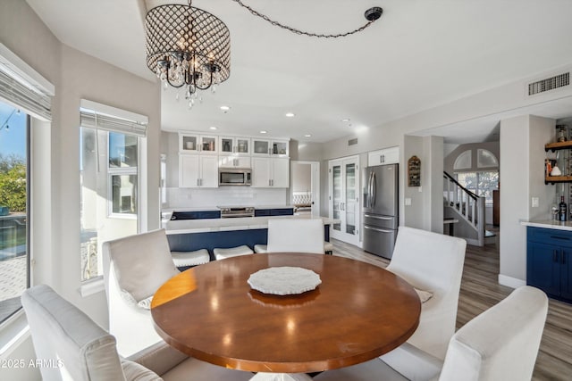 dining space featuring a notable chandelier, recessed lighting, visible vents, light wood-type flooring, and stairs