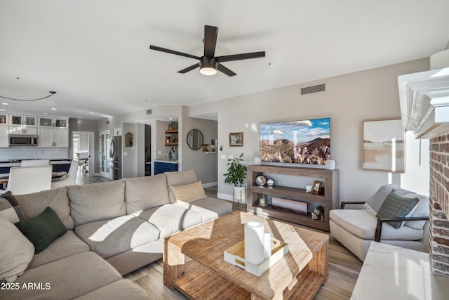 living area with baseboards, light wood-style flooring, visible vents, and a ceiling fan