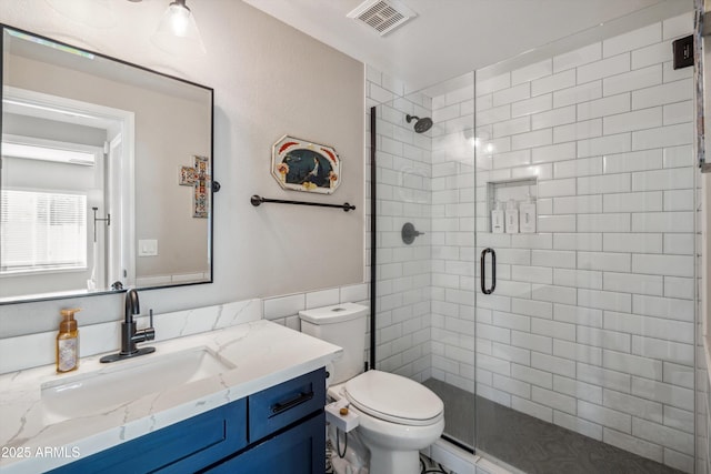 full bathroom with a shower stall, visible vents, vanity, and toilet