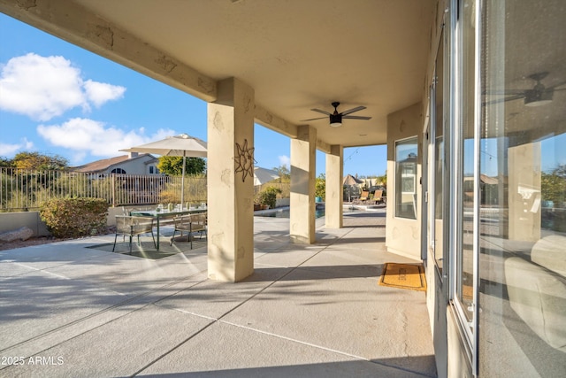 view of patio featuring outdoor dining area, fence, and a ceiling fan