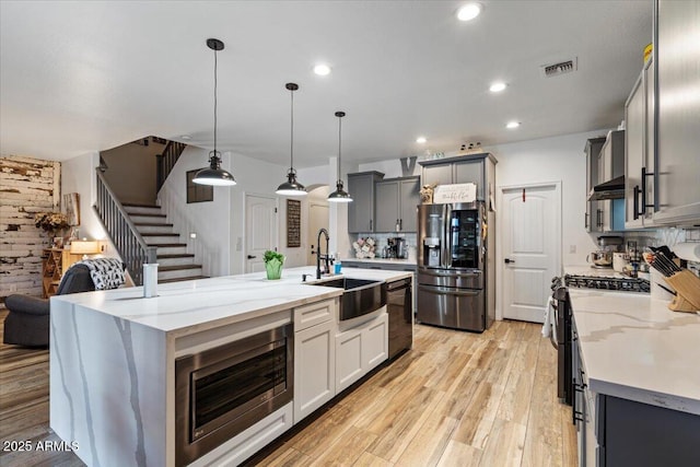 kitchen featuring a center island with sink, appliances with stainless steel finishes, sink, and pendant lighting