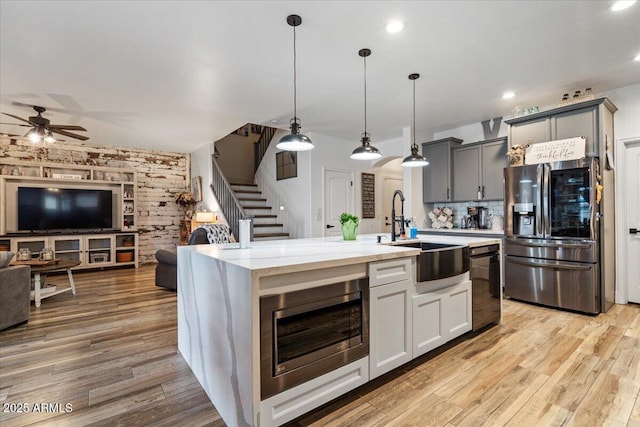 kitchen with stainless steel refrigerator with ice dispenser, sink, gray cabinetry, decorative light fixtures, and black dishwasher