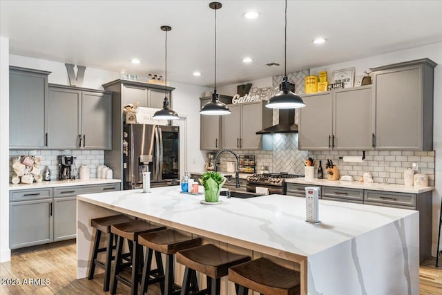 kitchen featuring a large island with sink, appliances with stainless steel finishes, a breakfast bar area, and decorative light fixtures