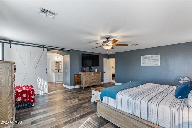 bedroom with a barn door and dark hardwood / wood-style floors