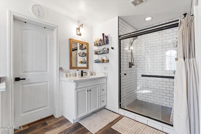 bathroom featuring wood-type flooring, vanity, a textured ceiling, and walk in shower