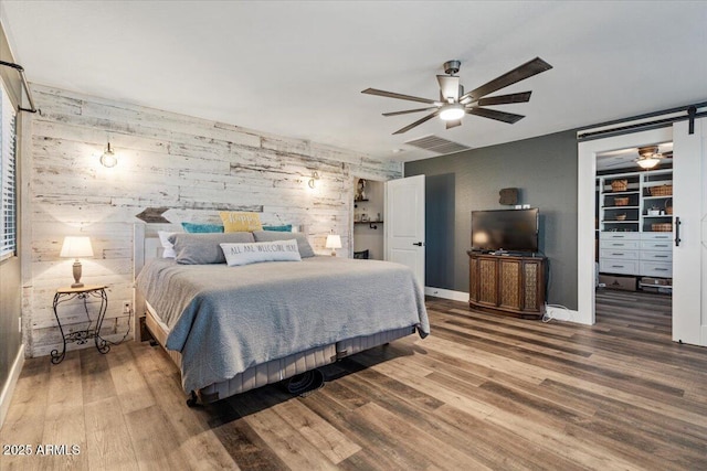 bedroom with hardwood / wood-style flooring, ceiling fan, and a spacious closet