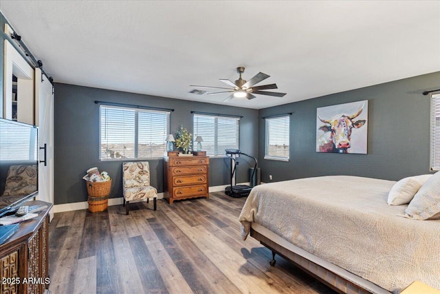 bedroom with hardwood / wood-style flooring, a barn door, and ceiling fan