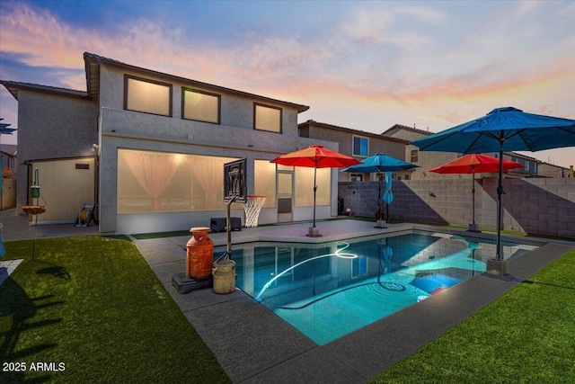 pool at dusk with a patio and a lawn