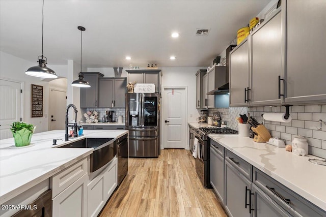 kitchen with sink, light hardwood / wood-style flooring, black gas range, stainless steel refrigerator with ice dispenser, and decorative light fixtures