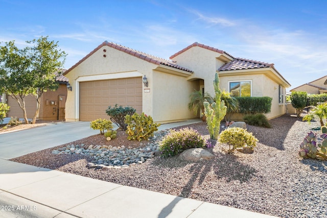 mediterranean / spanish house featuring driveway, an attached garage, a tile roof, and stucco siding