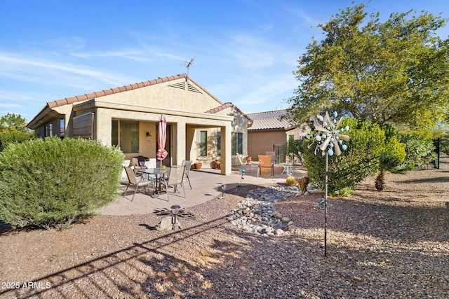 back of property with a patio area, a tiled roof, and stucco siding