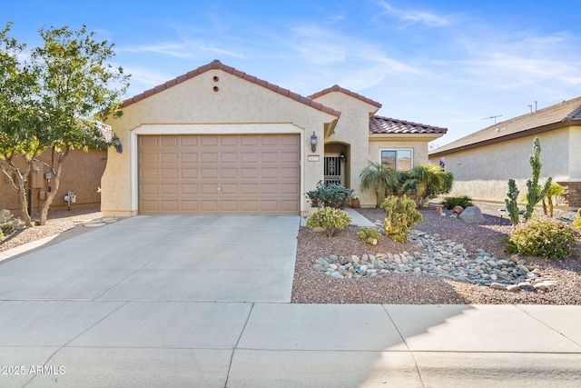 mediterranean / spanish home with a garage, driveway, a tiled roof, and stucco siding