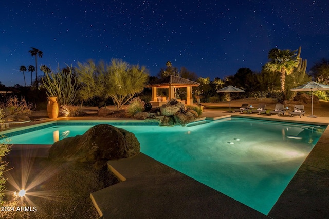 pool at night with an outdoor pool, a gazebo, and a patio area