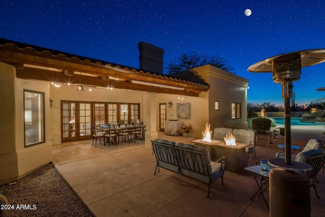 patio at twilight featuring an outdoor pool, outdoor dining space, and a fire pit